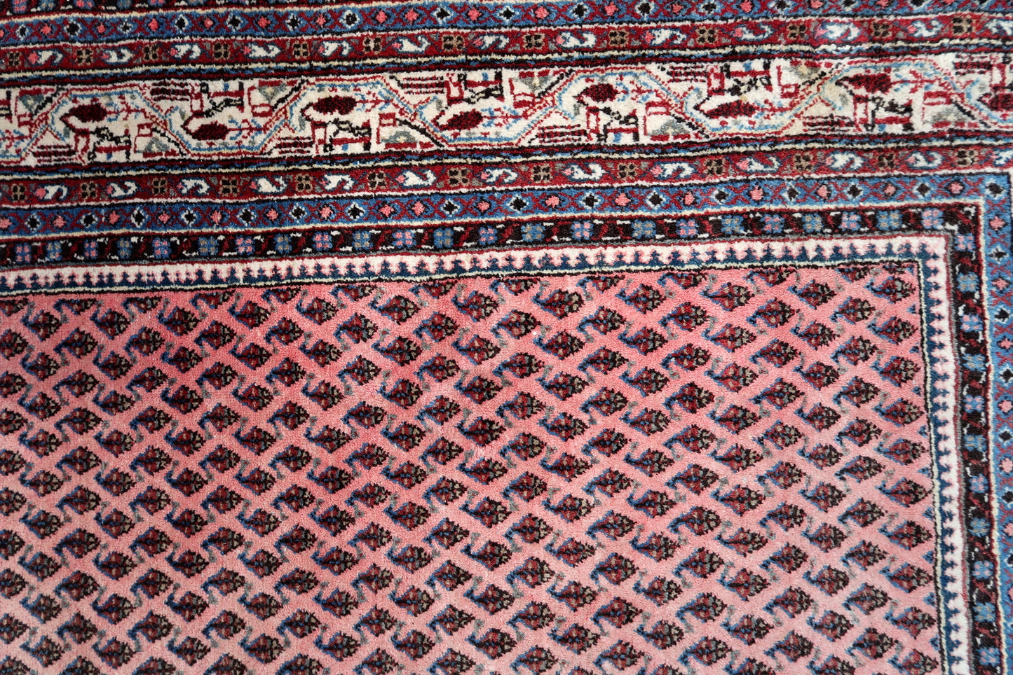 Handmade vintage Indian Seraband rug in original condition, it is unequally faded (one side is brighter then another) . The rug has been made in traditional pattern, it is from end of 20th century. The shades of the rug are mostly in pink and white. All-over design with repeating pattern. All dyes on this rug are natural. This is the type of rug woven in India to compete in the same market as rugs from Persia.