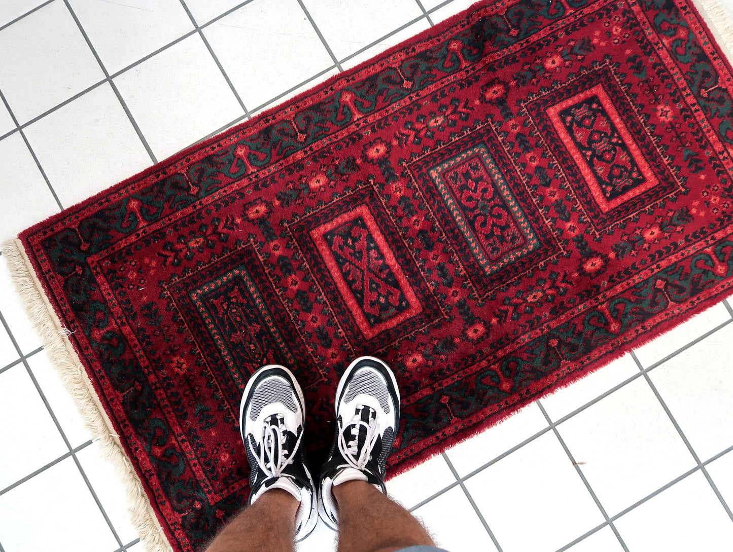 Vintage red woolen rug from Germany made in Baluch style. The rug is in deep red and emerald shades. It is from the middle of 20th century in original good condition.