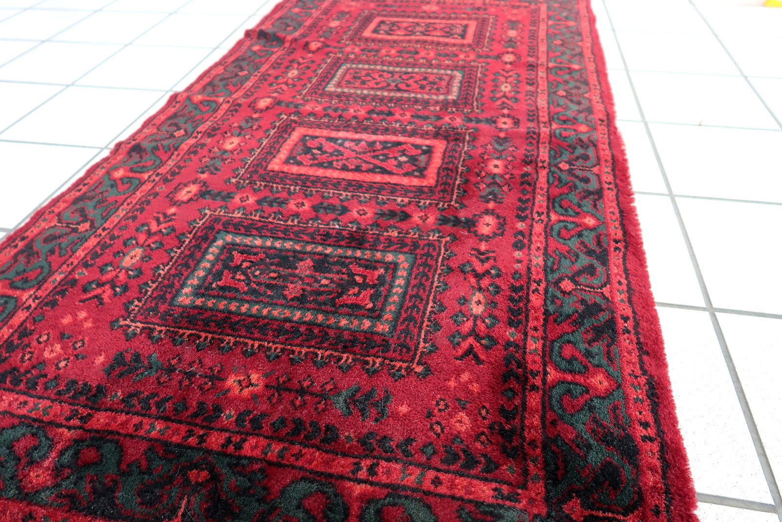 Vintage red woolen rug from Germany made in Baluch style. The rug is in deep red and emerald shades. It is from the middle of 20th century in original good condition.
