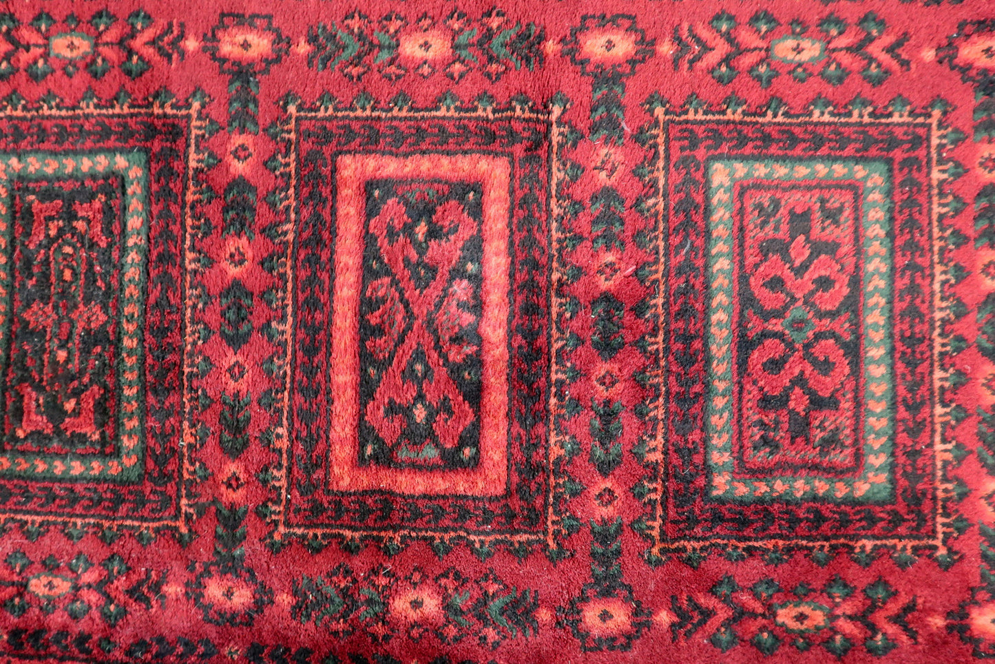 Vintage red woolen rug from Germany made in Baluch style. The rug is in deep red and emerald shades. It is from the middle of 20th century in original good condition.