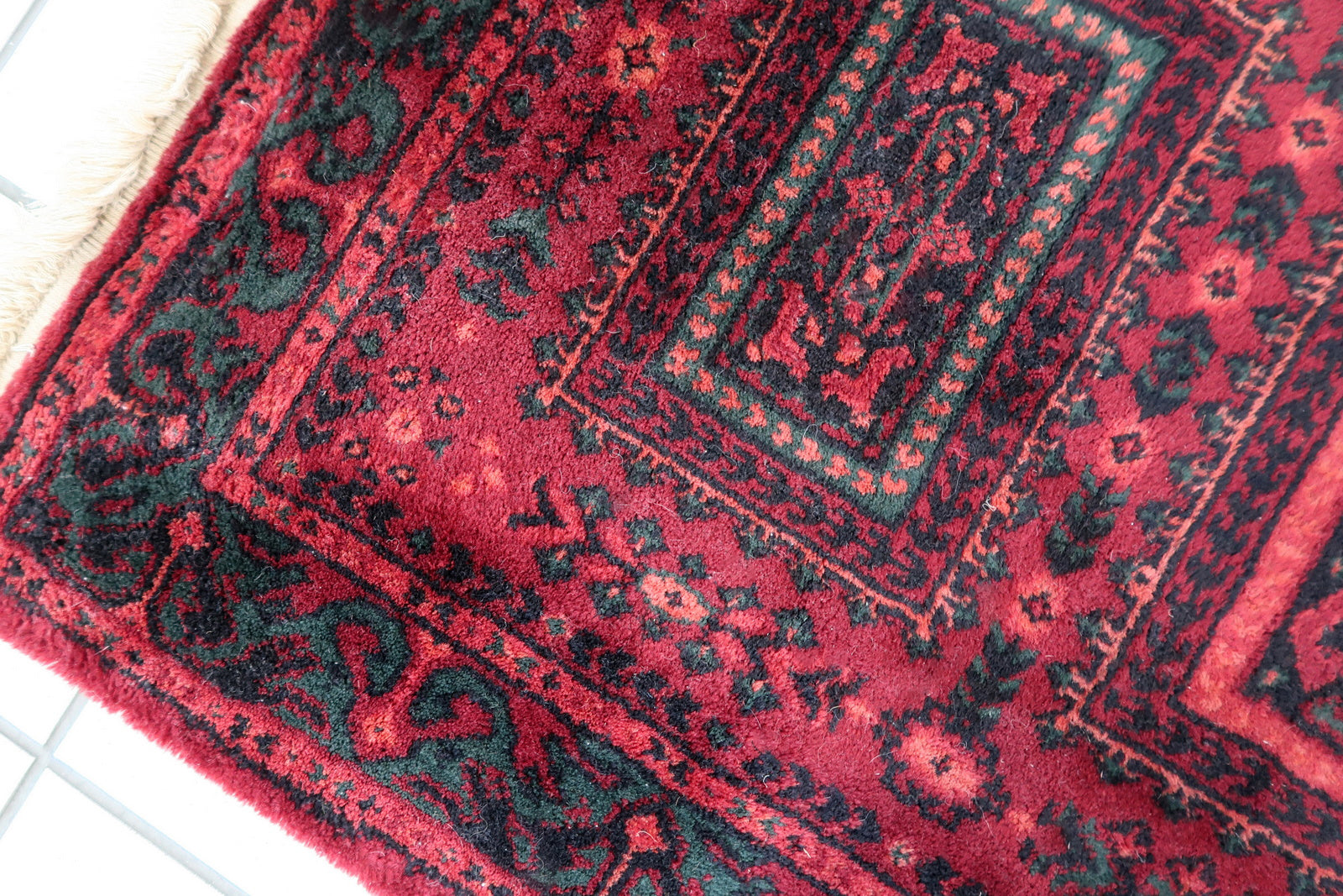Vintage red woolen rug from Germany made in Baluch style. The rug is in deep red and emerald shades. It is from the middle of 20th century in original good condition.