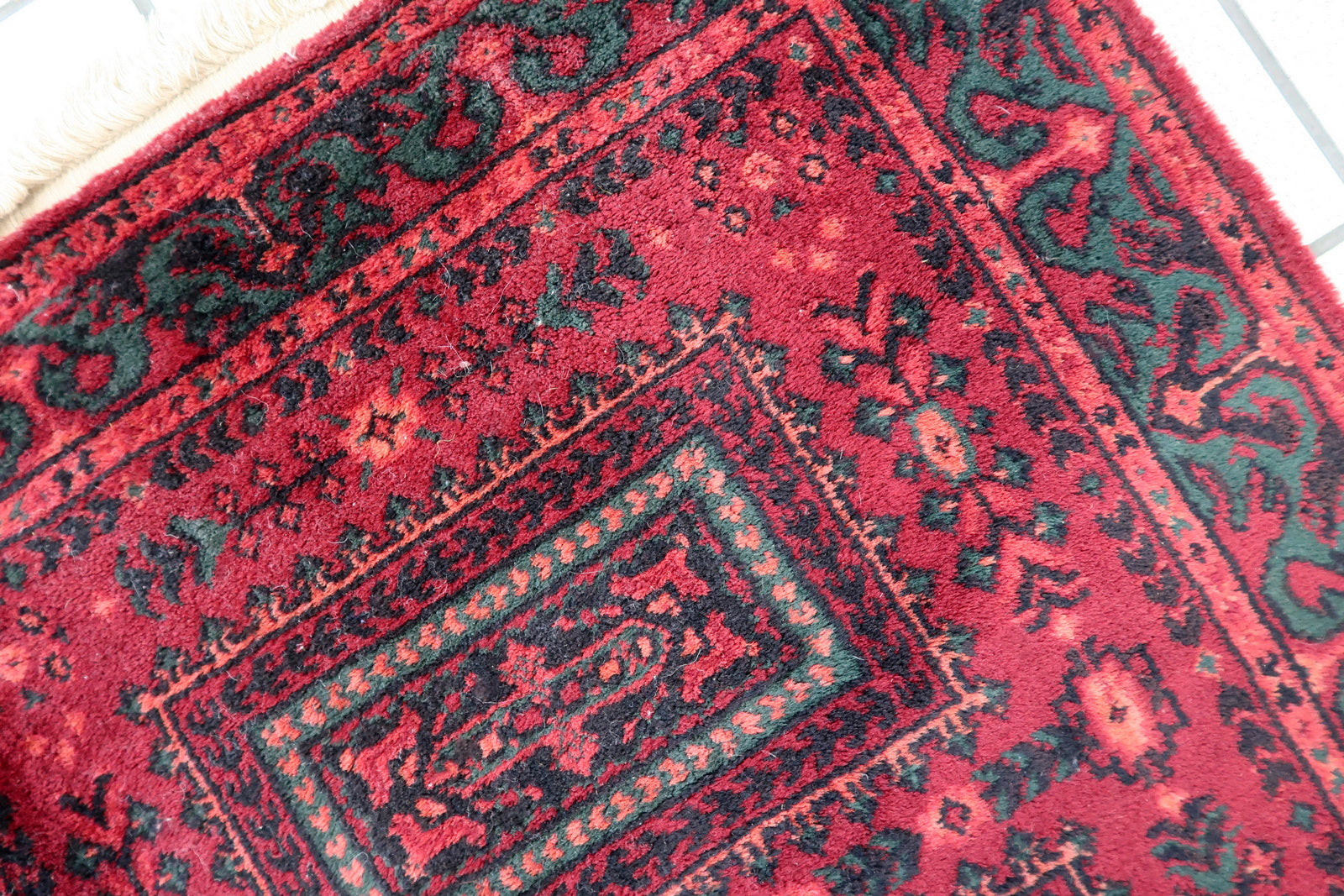 Vintage red woolen rug from Germany made in Baluch style. The rug is in deep red and emerald shades. It is from the middle of 20th century in original good condition.