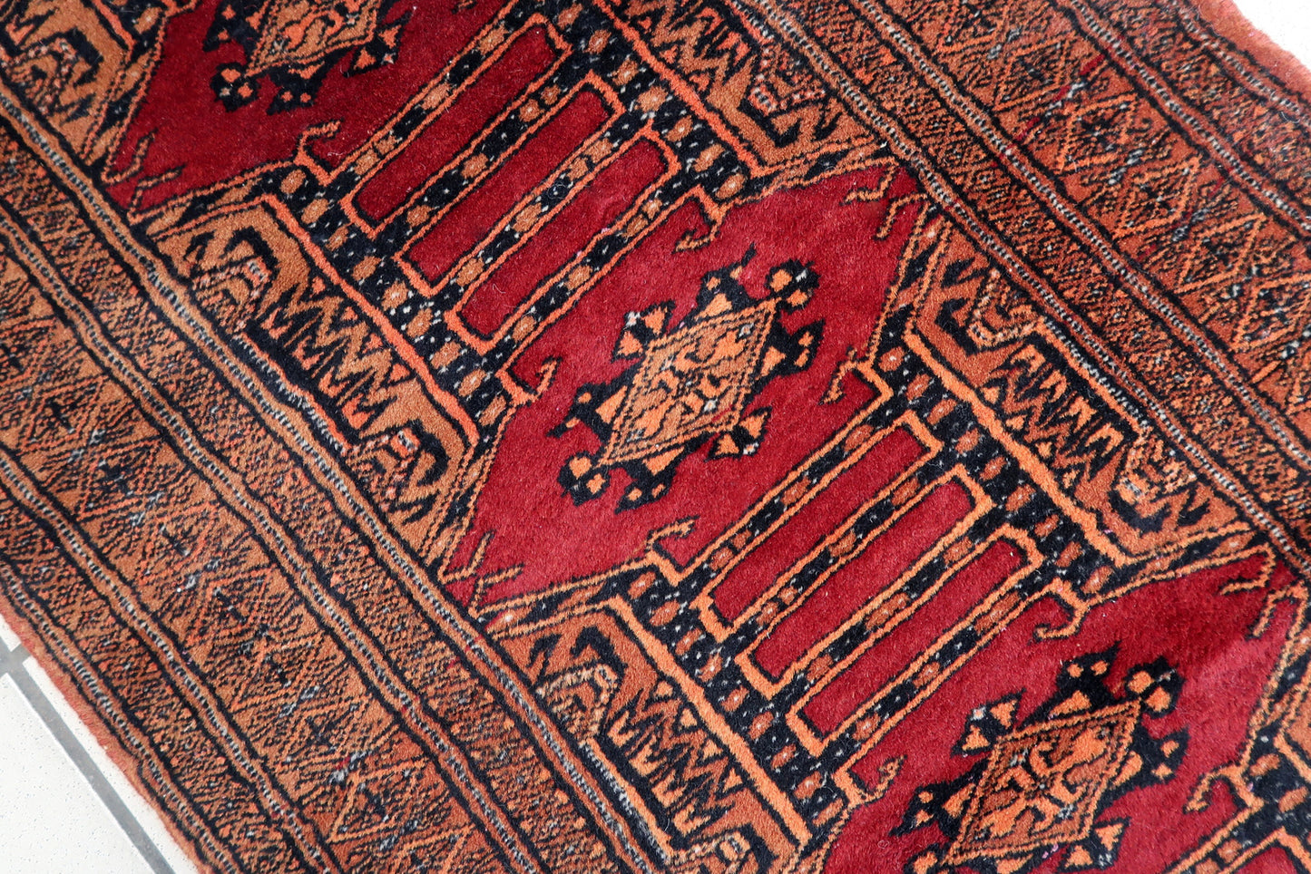 Handmade vintage Uzbek Bukhara narrow rug in red wool. The rug has unusual tribal design. It is from the end of 20th century, in original good condition.