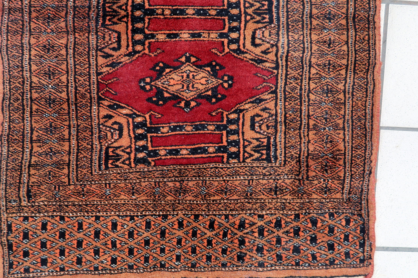 Handmade vintage Uzbek Bukhara narrow rug in red wool. The rug has unusual tribal design. It is from the end of 20th century, in original good condition.
