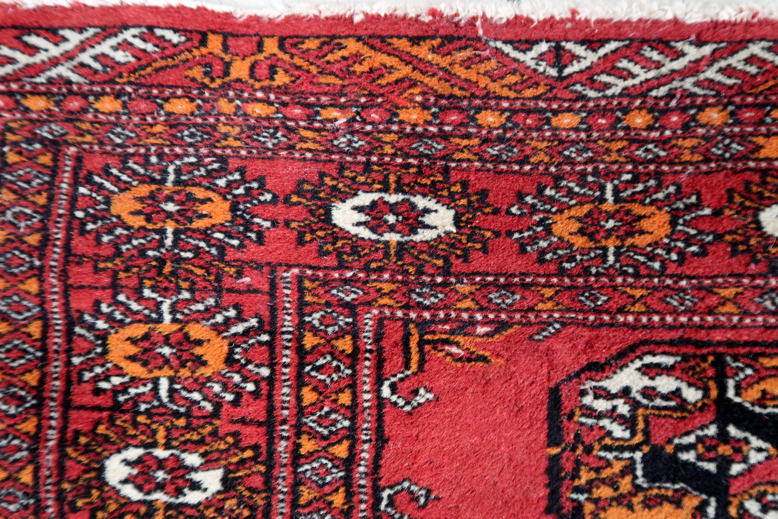 Handmade vintage Uzbek Bukhara rug in traditional design and red wool. The rug is from the end of 20th century. It is in original condition, has some low pile.