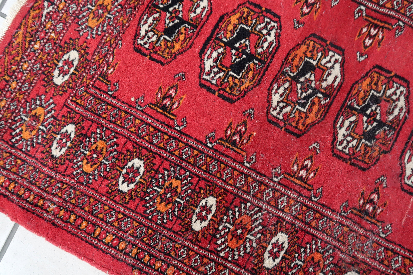 Handmade vintage Uzbek Bukhara rug in traditional design and red wool. The rug is from the end of 20th century. It is in original condition, has some low pile.