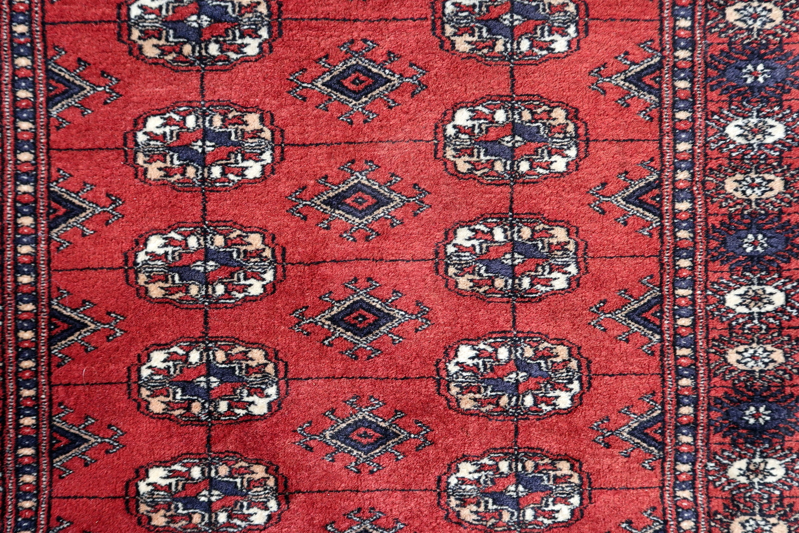 Handmade vintage red rug in Bukhara design. The rug is in original good condition, from the end of 20th century.