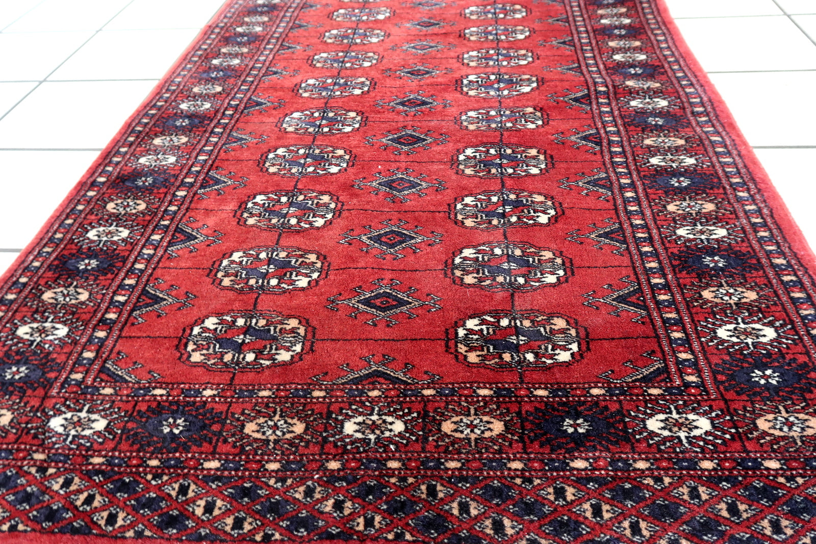 Handmade vintage red rug in Bukhara design. The rug is in original good condition, from the end of 20th century.