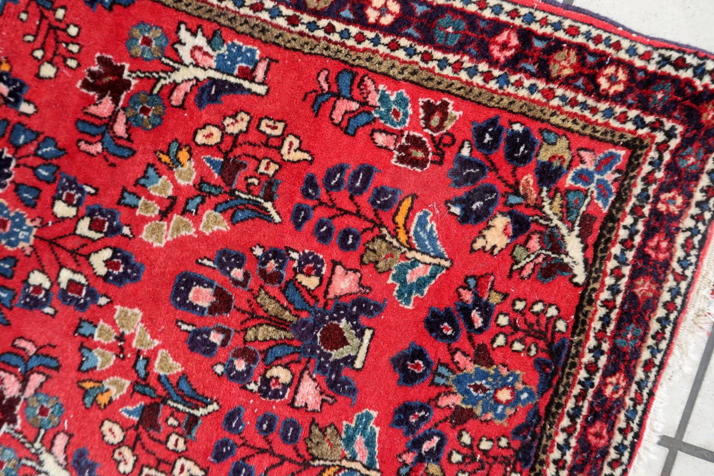 Handmade vintage Sarouk rug in traditional design. The rug is in red color. The rug is from the end of 20th century in original good condition.