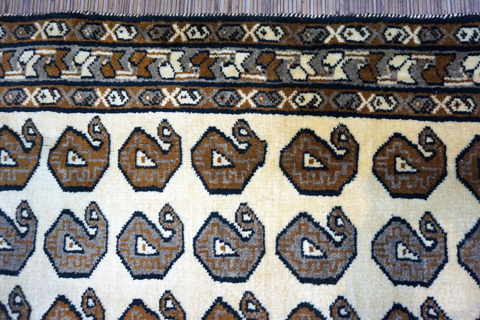 Handmade vintage Persian Gabbeh rug in beige color with repeating paisley design. The rug is from the end of 20th century in original good condition.