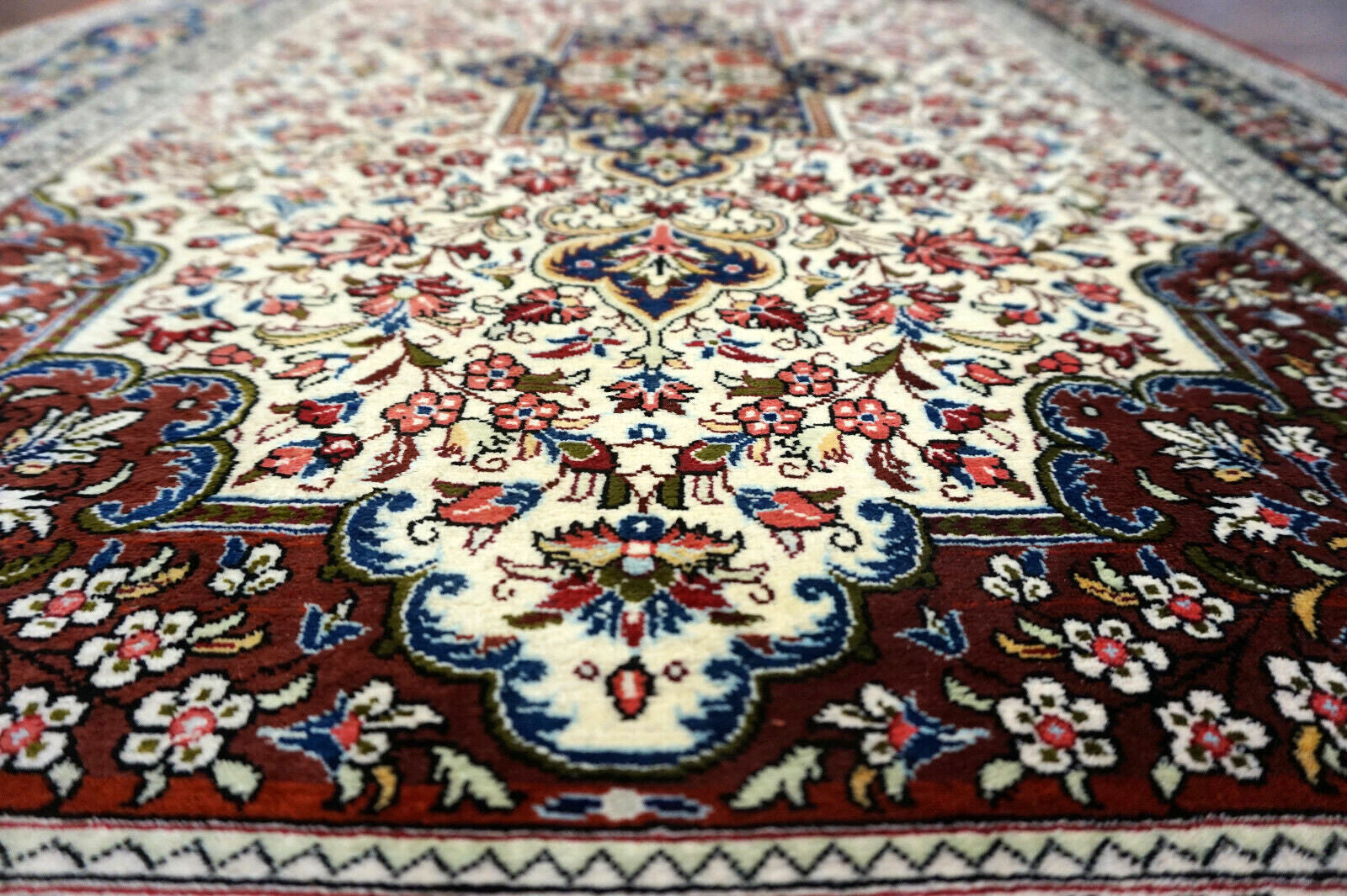 Handmade vintage Persian Qum rug in very busy floral design with natural colors. The rug has been made in silk. It is is from the end of 20th century in original good condition.