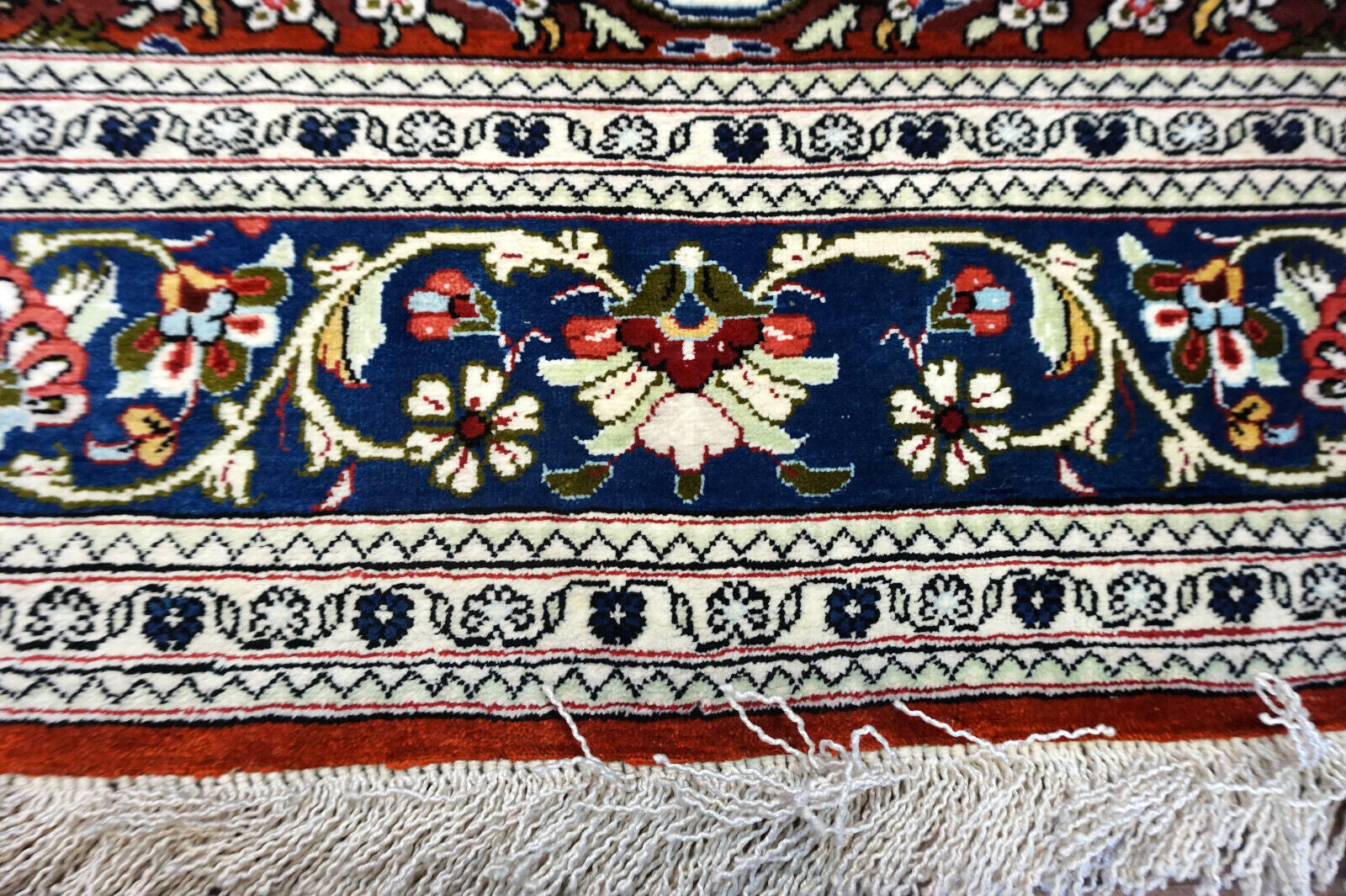 Handmade vintage Persian Qum rug in very busy floral design with natural colors. The rug has been made in silk. It is is from the end of 20th century in original good condition.
