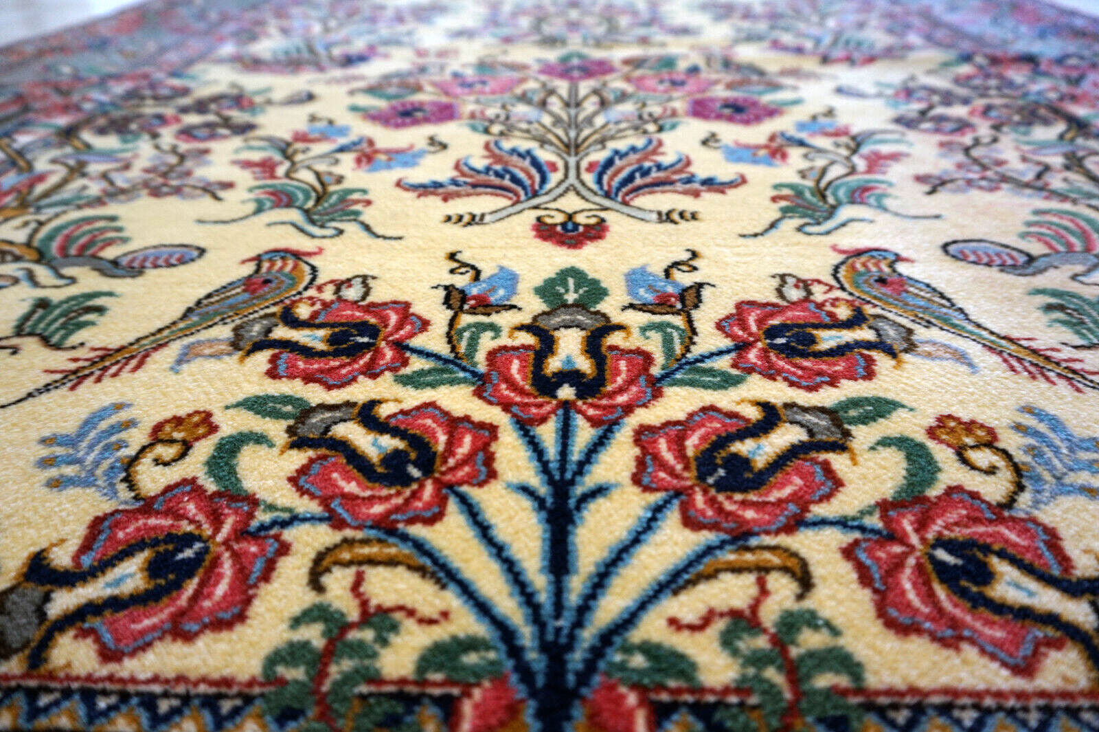 Close-up of the colorful flowers and birds design on the vintage Qum rug.