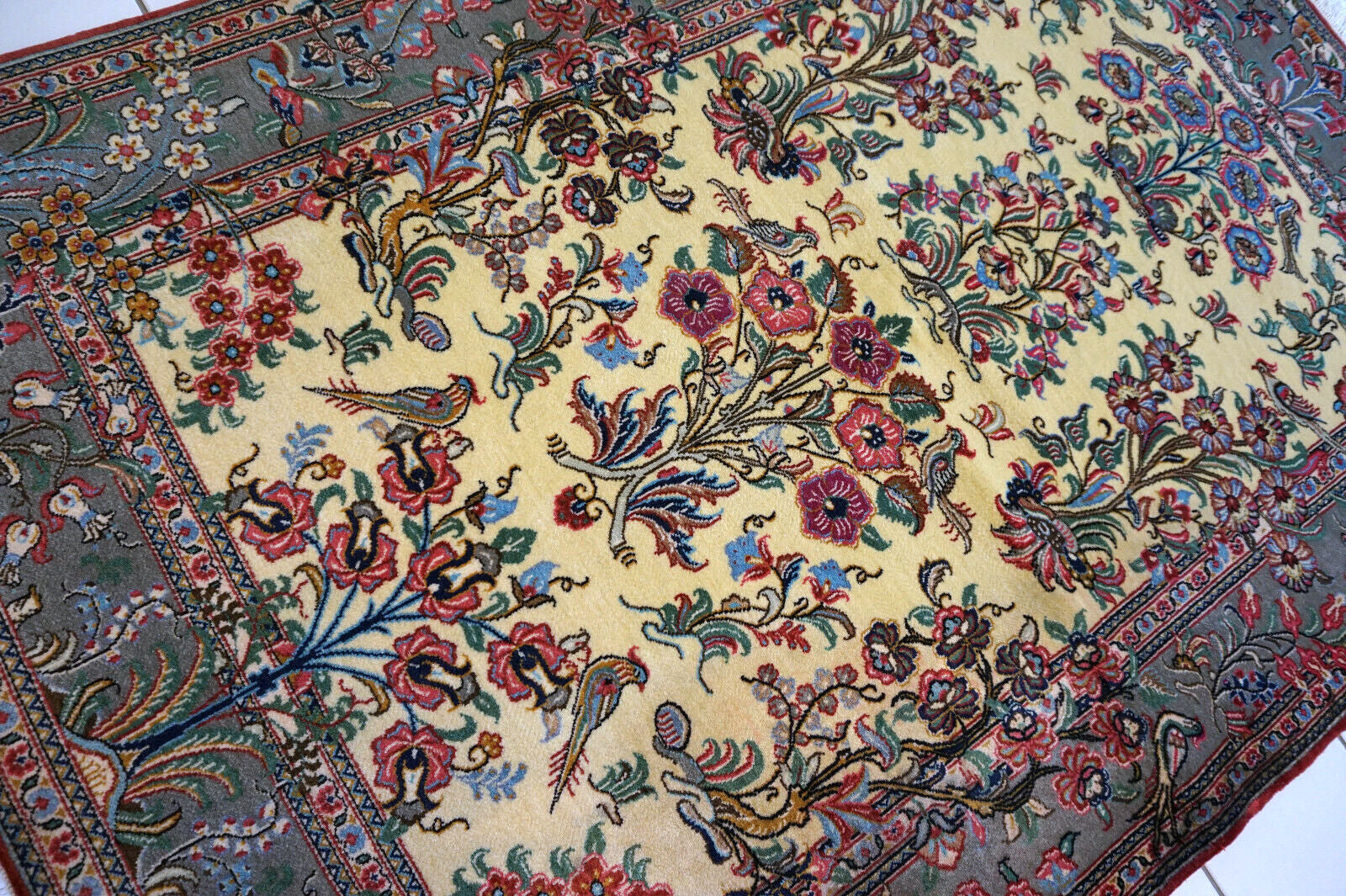 Close-up of the colorful flowers and birds design on the vintage Qum rug.
