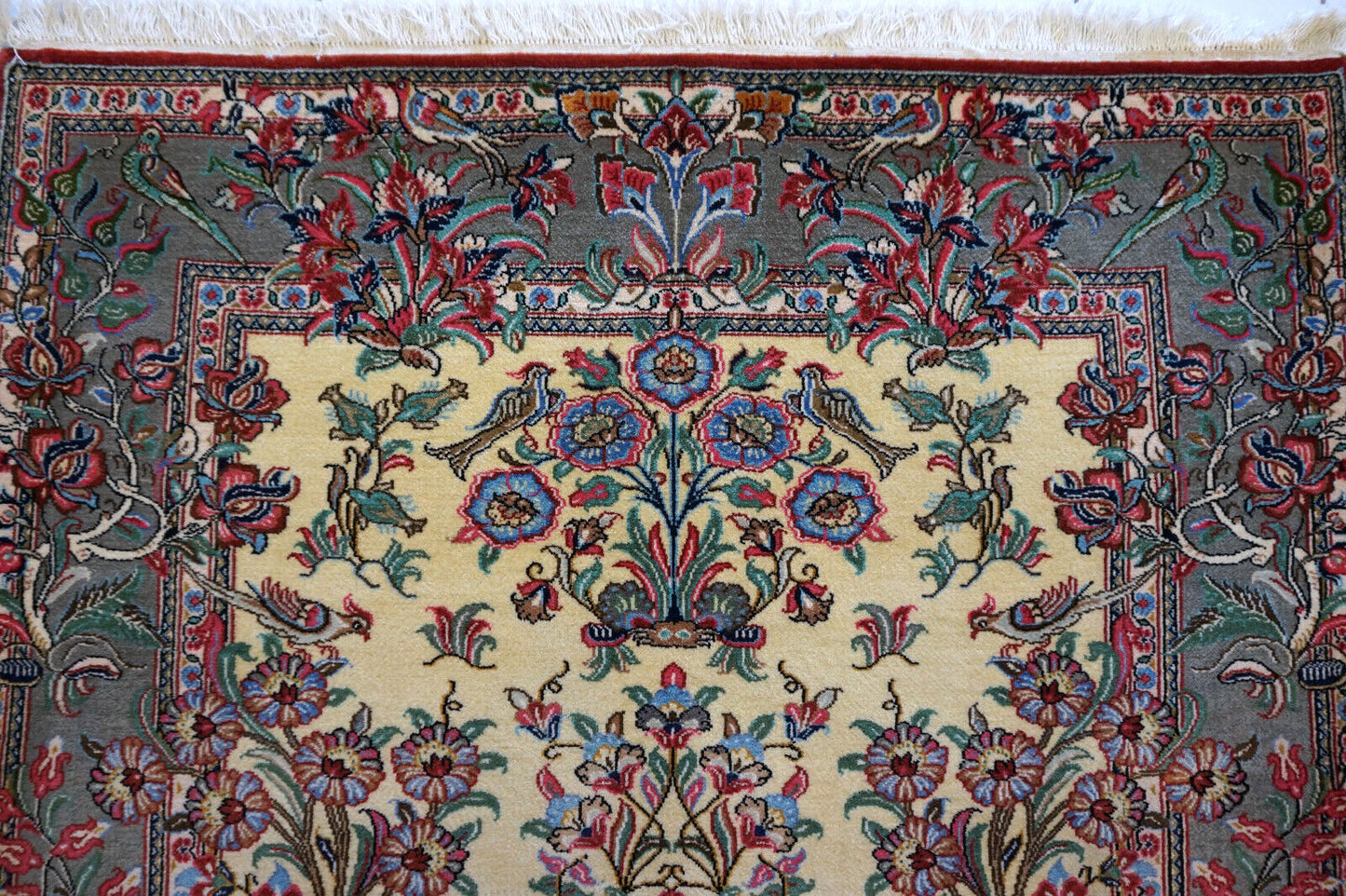 Close-up of the colorful flowers and birds design on the vintage Qum rug.
