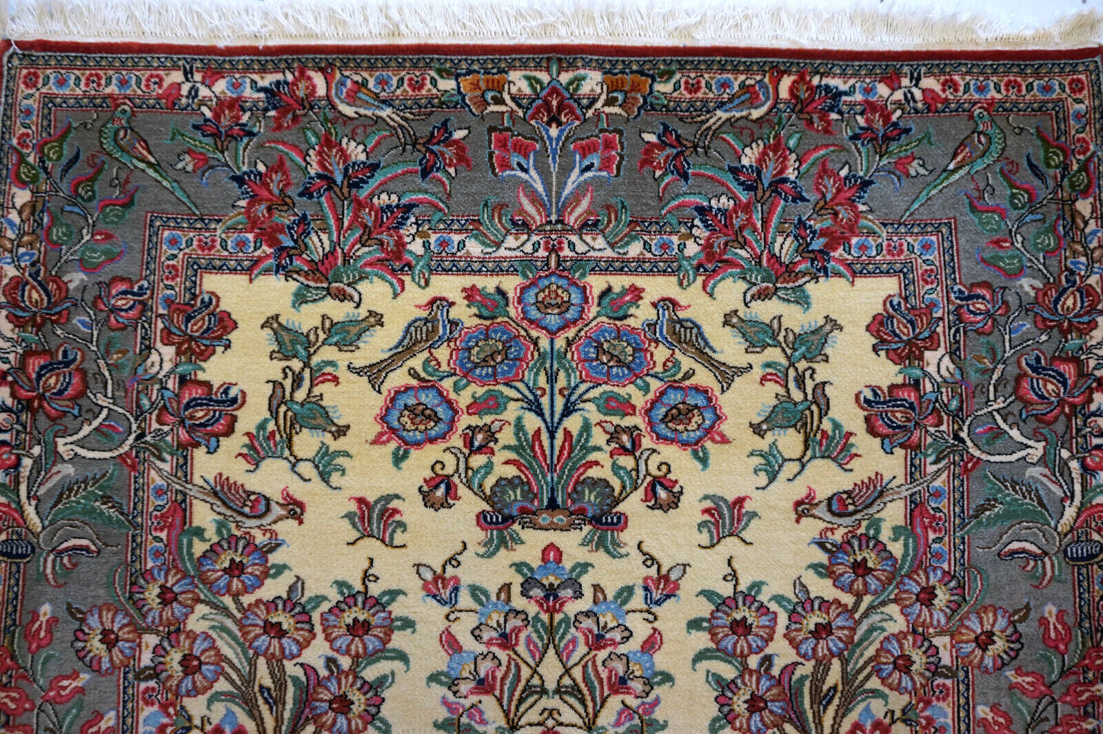 Close-up of the colorful flowers and birds design on the vintage Qum rug.