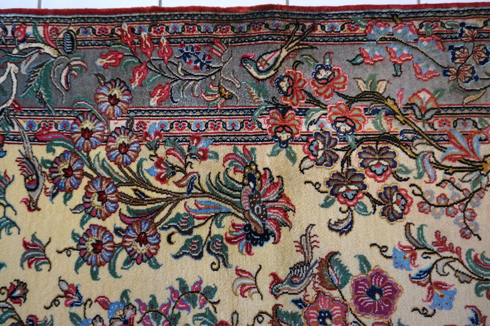 Close-up of the colorful flowers and birds design on the vintage Qum rug.