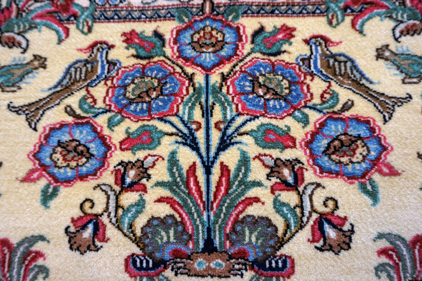 Close-up of the colorful flowers and birds design on the vintage Qum rug.