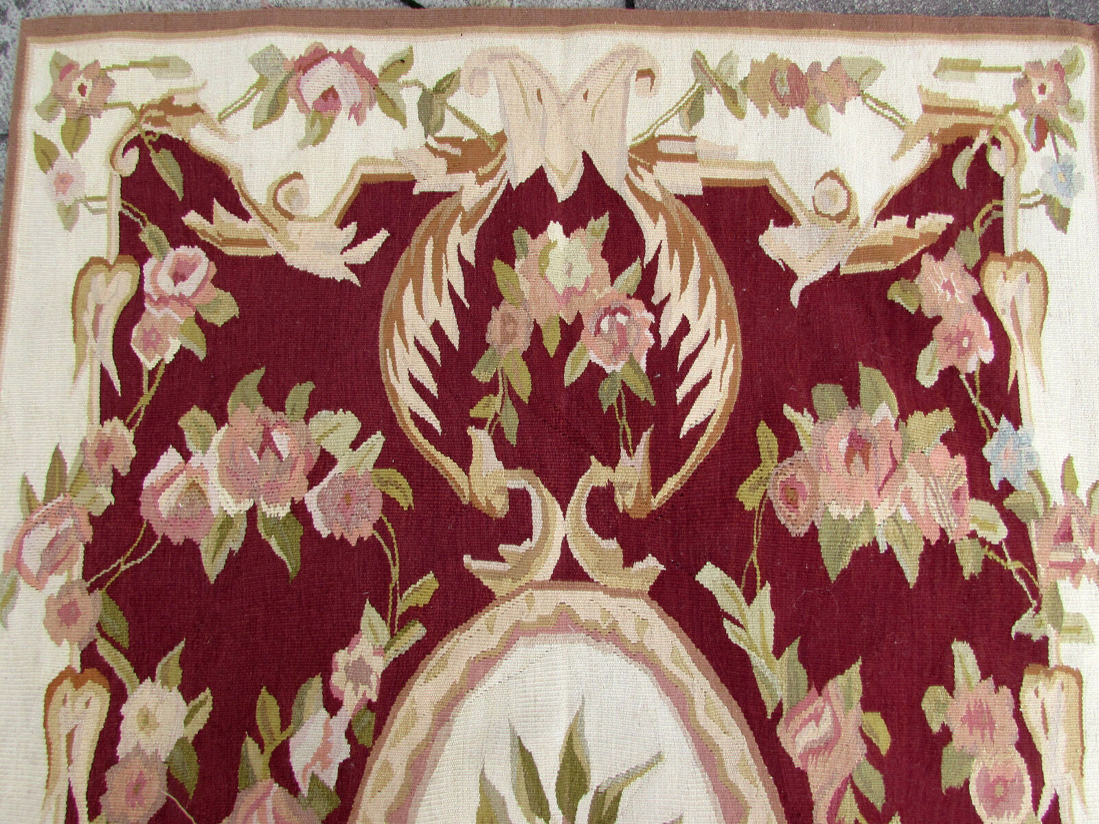 Close-up of intricate Aubusson rug design in beige and burgundy colors.