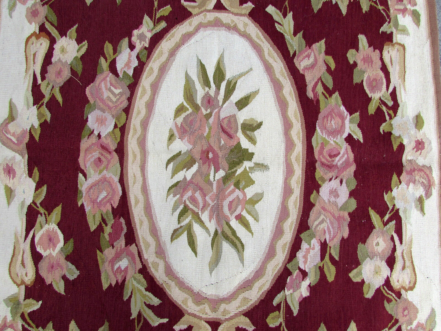 Detail of handmade wool rug from France with olive green and rose accents.