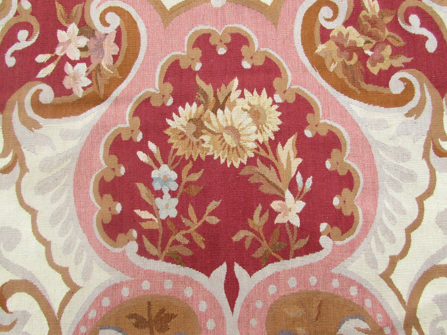 The warm and inviting color combination of red, beige, and olive brown in the Aubusson Rug